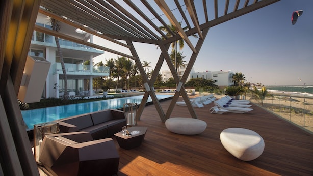 Une terrasse en bois avec des chaises longues et une piscine.
