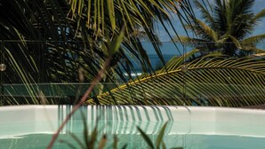 Una piscina con acqua cristallina, circondata da palme e vista sull'oceano.