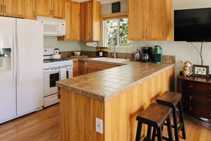 A kitchen with wooden cabinets, a white refrigerator, a stove, a microwave, a sink, and a coffee maker. - Peaceful Mountain Sanctuary w/central heat,AC,fireplace near Arrowhead Village (Lake Arrowhead)
