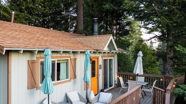 Eine Holzterrasse mit Sitzgelegenheiten im Freien, ein überdachter Bereich mit einer Tür und ein Schornstein.