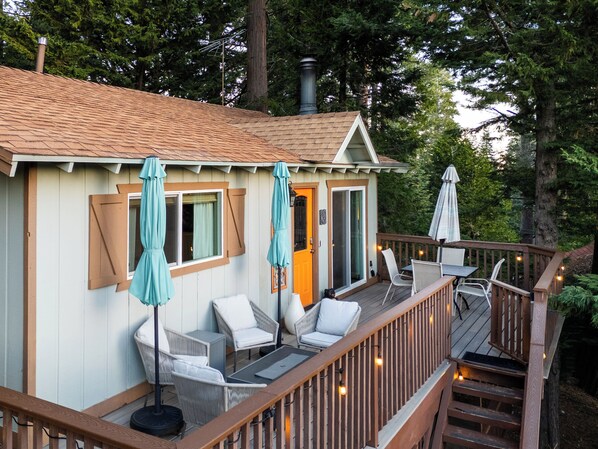 A wooden deck with outdoor seating, a covered area with a door, and a chimney. - Peaceful Mountain Sanctuary w/central heat,AC,fireplace near Arrowhead Village (Lake Arrowhead)