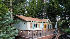 Eine Holzhütte mit einer Holzterrasse, einer Treppe und einem kleinen Veranda-Bereich.