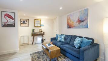 A modern living room with a dark blue sofa, a wooden coffee table, and a large abstract painting.