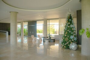 Eine geräumige Lobby mit einem großen Weihnachtsbaum, modernen Möbeln und großen Fenstern mit Blick ins Freie.