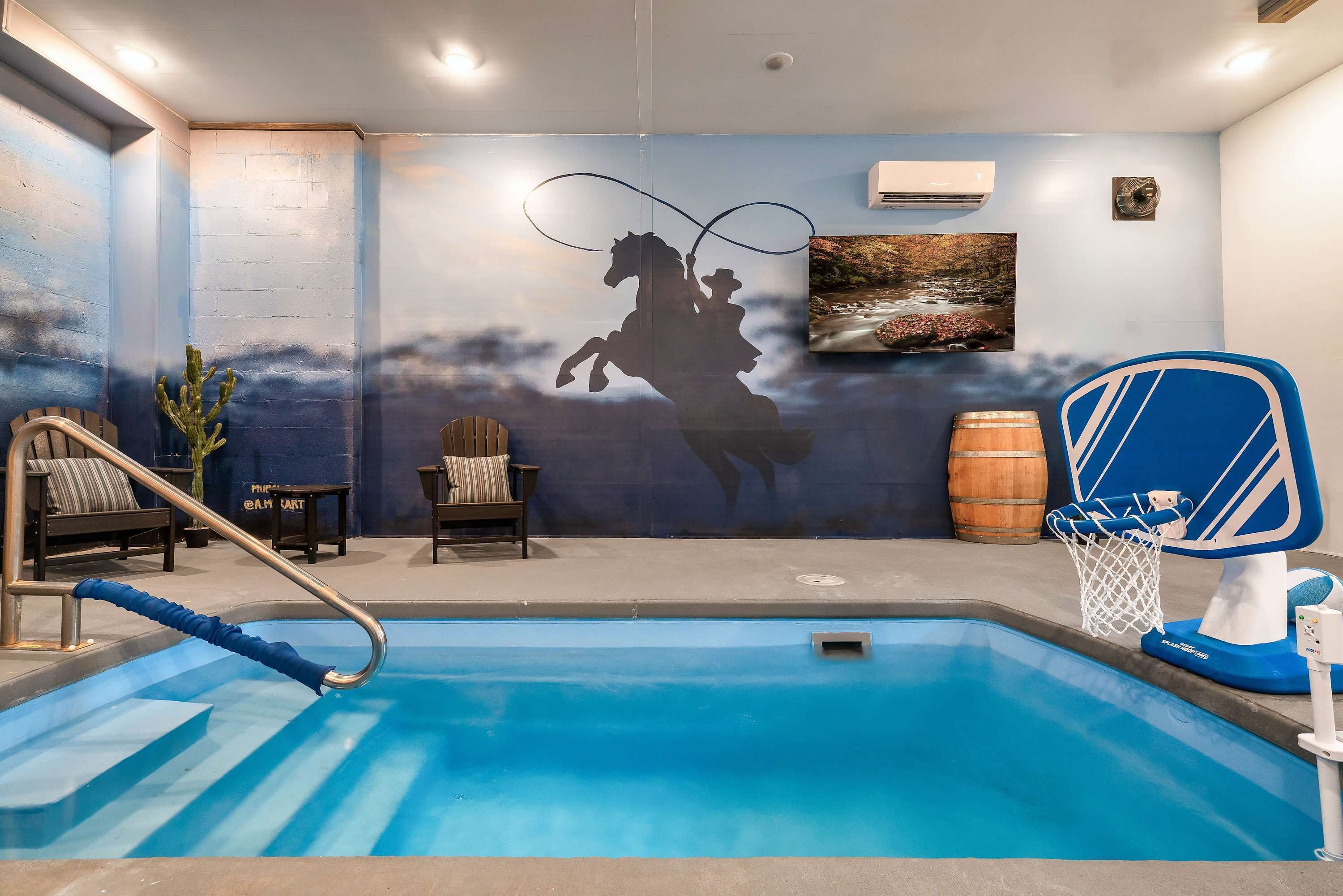 A swimming pool with a blue and white mural, a basketball hoop, and a wooden barrel.
