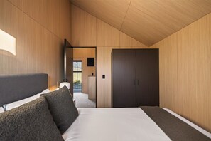 A modern bedroom with a bed, a wardrobe, and a view through a window.
