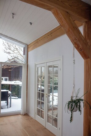 A room with a wooden ceiling, a sliding glass door, and a hanging plant.