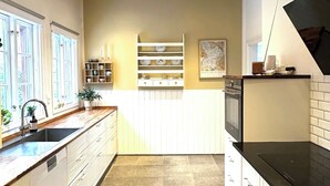 A kitchen with white cabinets, a black countertop, a tiled floor, and a ceiling with recessed lighting. - Spacious holiday home near beach and nature (Jægerspris)