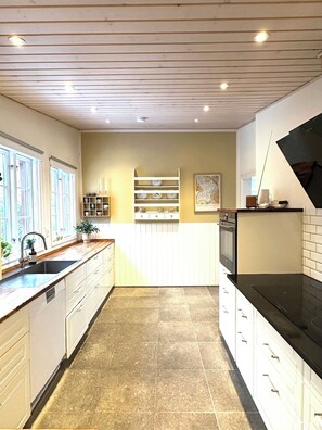 A kitchen with white cabinets, a black countertop, a tiled floor, and a ceiling with recessed lighting. - Spacious holiday home near beach and nature (Jægerspris)