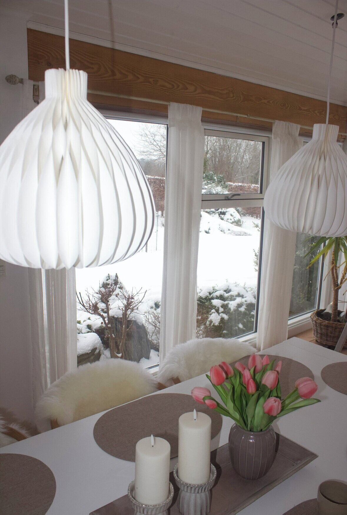 A dining area with a table, candles, and a vase of tulips.