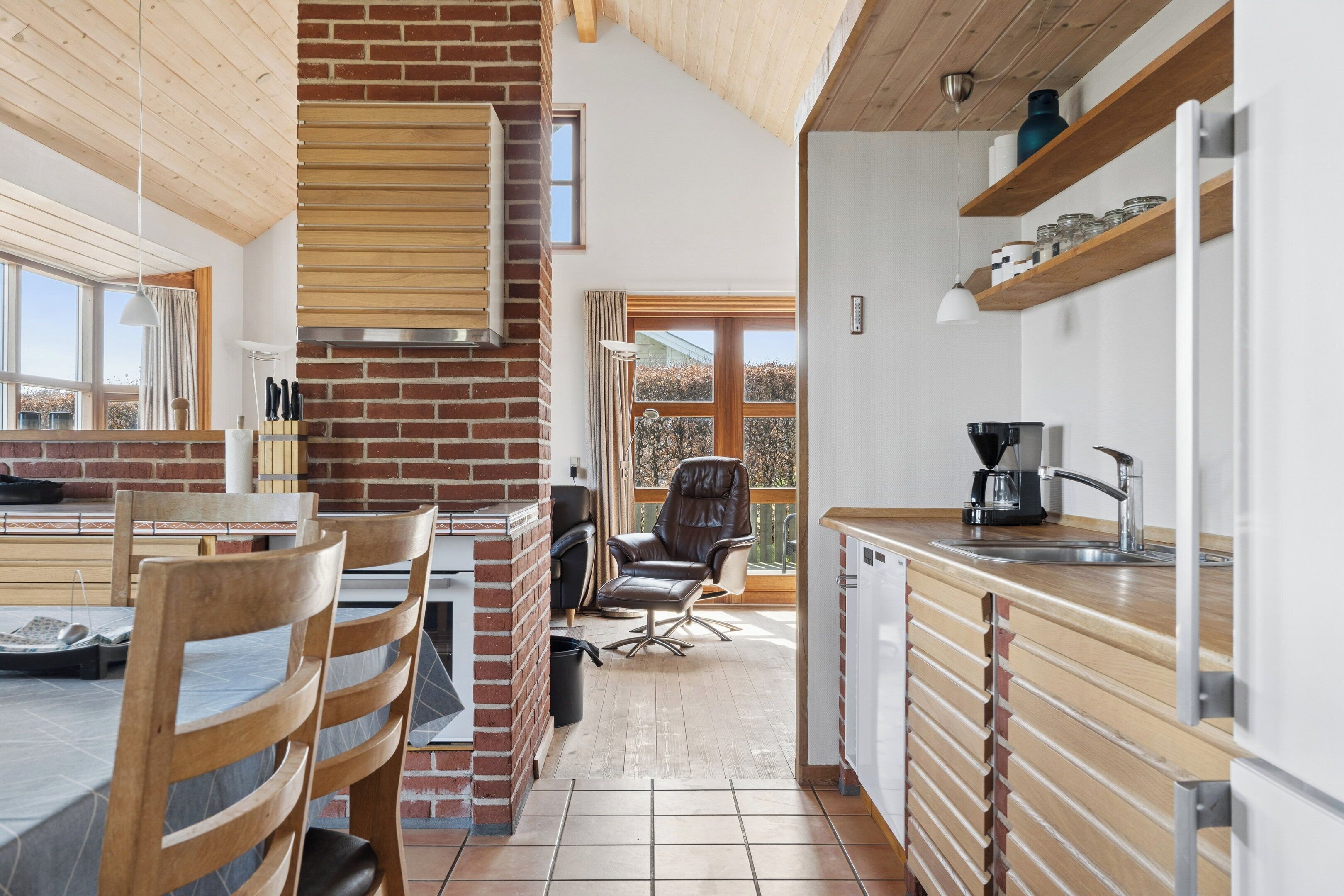 Eine moderne Küche mit Backsteinwand, Holzboden und einem Essbereich mit Stühlen und Tisch.