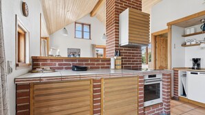 Una cocina con horno de ladrillo, armarios de madera y un ventanal.