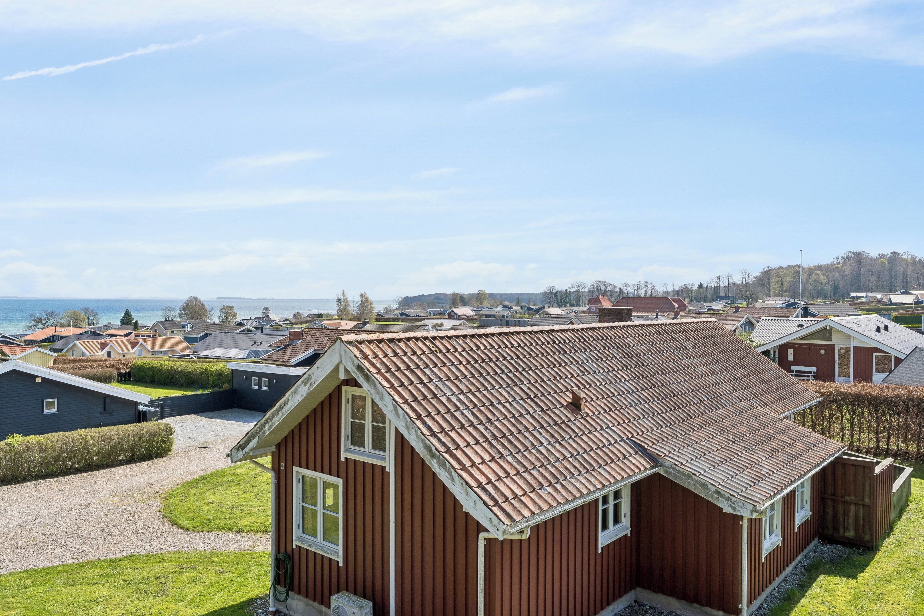 A residential area with houses, a clear sky, and a body of water in the background.