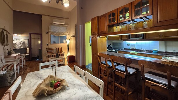 Una cocina amplia con armarios de madera, encimera de mármol y un comedor con mesa y sillas.