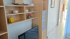 Una sala de estar moderna con televisor de pantalla plana, estantes de madera y piso de baldosas.