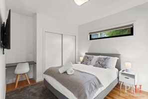 Une chambre moderne avec un lit, des tables de chevet, un bureau et un téléviseur.