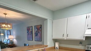 Una cucina moderna con mobili bianchi, una lavastoviglie in acciaio inossidabile e un lavello a due vasche.