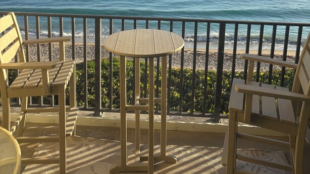 Un balcone con tavolo e sedie affacciato sull'oceano.