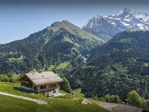 A mountain cabin with a sloped roof, wooden exterior, and a balcony.