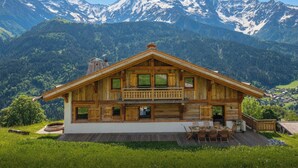 Eine Holzchalet mit Balkon, Terrasse und Blick auf schneebedeckte Berge.