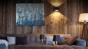 Ein modernes Wohnzimmer mit einer Holzwand, einem großen abstrakten Gemälde, einer Couch mit Kissen, zwei Stehlampen und einem Couchtisch aus Holz mit Dekorationen.