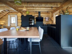 Une cuisine moderne avec un plafond en bois, une table à manger avec des chaises et un réfrigérateur.