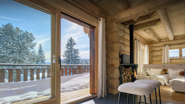 En hytte med veranda, pejs og hyggeligt opholdsområde.