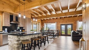 Una cocina amplia con una isla de piedra, taburetes de madera y un comedor grande con vistas.