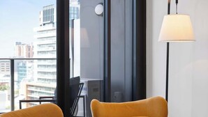 A modern room with two mustard-colored armchairs, a floor lamp, and a large window offering a city view. - Prime 2BR City Escape Walkable CBD Free Parking (Adelaide)