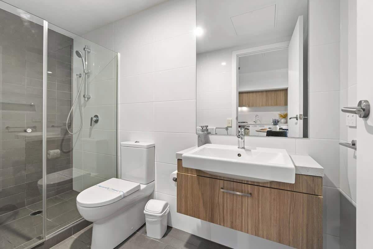 A modern bathroom with a glass-enclosed shower, a toilet, a sink, and a vanity with a mirror.