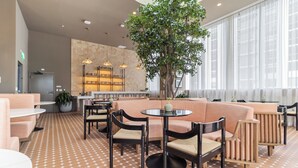 A modern lounge area with a patterned floor, seating arrangements, and a large tree. - Modern 1BR at The Crosby - Rooftop Pool, Gym & Walk to Bayside, Miami (Miami)