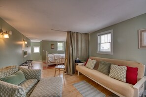 Ein gemütliches Zimmer mit Bett, Sofa, Sessel und kleinem Tisch.