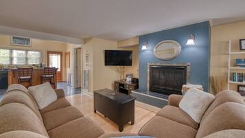 A living room with a fireplace, a television, and a dining area with chairs.