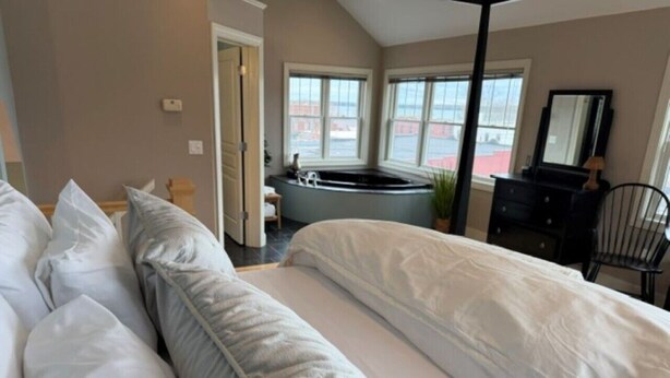 Une chambre d’hôtel avec un grand lit, un coin salon avec vue et une baignoire.