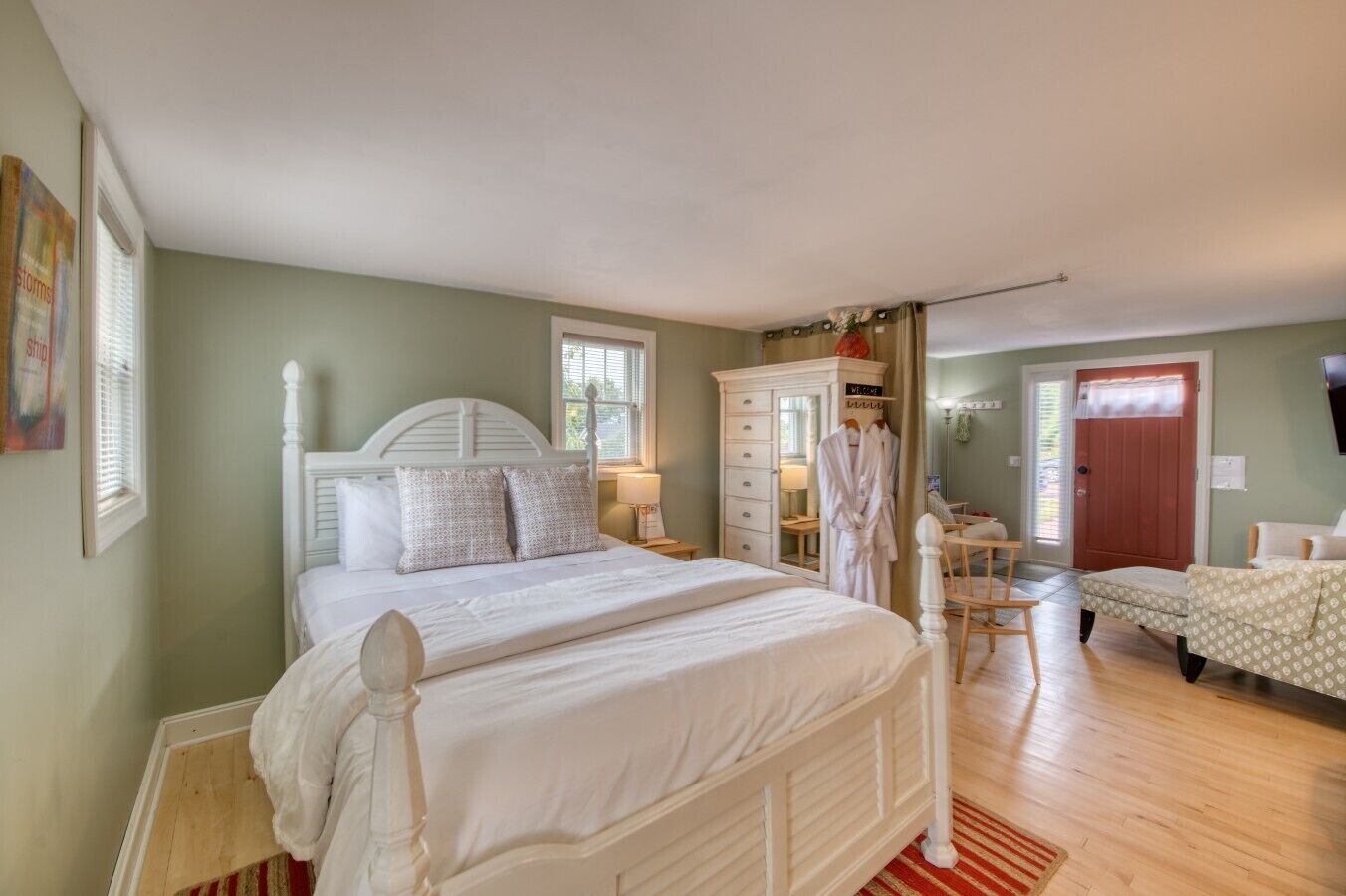A bedroom with a large bed, a wardrobe, a dressing table, and a red door.