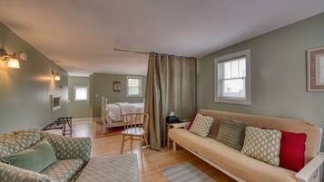 A cozy room with a bed, a sofa, a chair, and a small table.