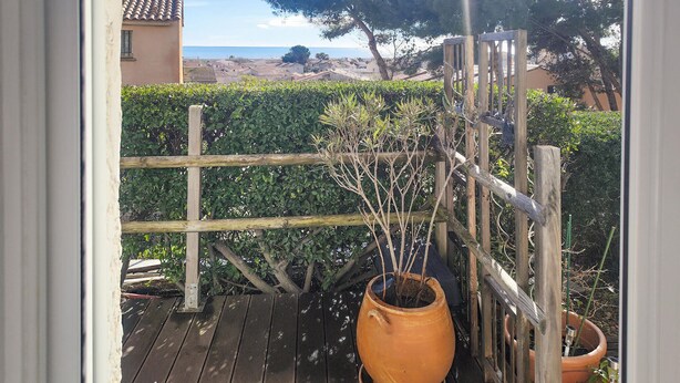 Una terraza de madera con una planta en maceta y una valla de madera.