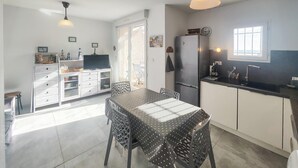 Una cocina moderna con comedor, que cuenta con una mesa grande, sillas, un refrigerador y un ventanal.