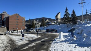 A snowy parking lot with a building in the background.