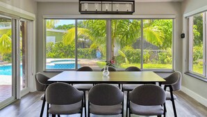 A dining area with a table and chairs, large windows with a view of a swimming pool and greenery. - Tranquil 4-bedroom house with heated pool and spa in Fort Lauderdale (Fort Lauderdale)