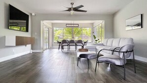 A spacious living room with a large window, a ceiling fan, and a modern sofa. - Tranquil 4-bedroom house with heated pool and spa in Fort Lauderdale (Fort Lauderdale)