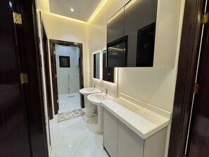 A modern bathroom with two sinks, a large mirror, and a shower. - Luxury apartments (Madinah)