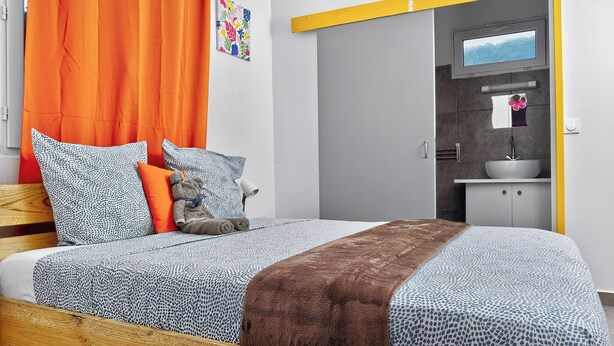 Ein modernes Schlafzimmer mit einem hölzernen Bettgestell, gemusterten Betttextilien und einem Teddybären.
