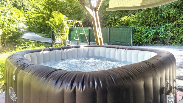 A hot tub in a garden with a wooden pergola overhead. - TERAKOTA Village Créole jacuzzis-plage (Deshaies)