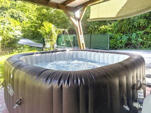 Ein Whirlpool in einem Garten mit einem überdachten Holz-Pergola.