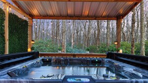 A hot tub under a wooden pergola with a forest backdrop. - Family Retreat Near Waterparks & Hiking with HotTub (Tobyhanna)