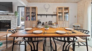 A dining area with a wooden table set for six, black chairs, a mounted deer head, and built-in wooden cabinets with glass doors. - Family Retreat Near Waterparks & Hiking with HotTub (Tobyhanna)