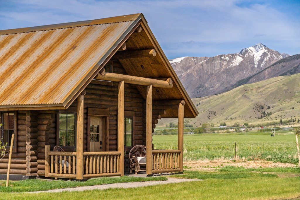 Eine rustikale Holzhütte mit Metalldach, einer Holzterrasse und Blick auf Berge im Hintergrund.