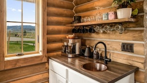 A wooden cabin interior with a kitchen area featuring a coffee maker, kettle, and a sink. - Copper Rose Ranch (Livingston)