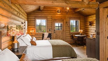 A log cabin interior with a bed, a dining table, and a fireplace.